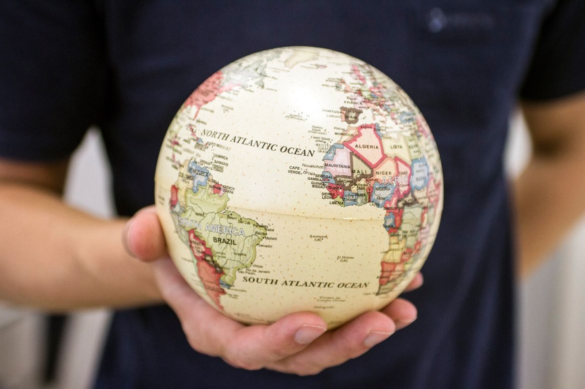 Imagem de uma pessoa segurando um globo terrestre na palma da mão